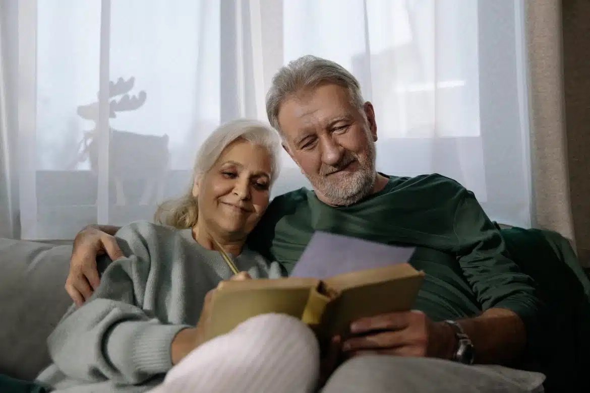 Man in Green Sweater Holding Book Beside Woman in White Sweater